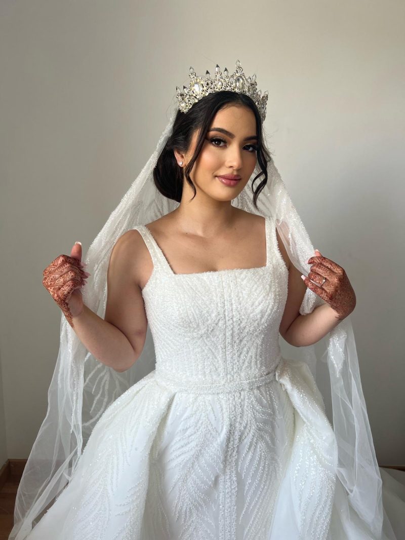 Mariee couronnee, voile de tulle et mains au henne, en robe bustier perlee a jupe volumineuse